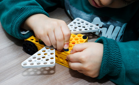 A little boy sits at a table and collects a construction kit