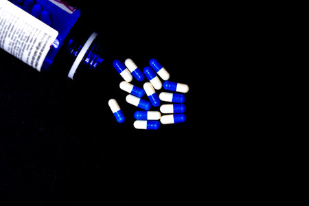 blue and white medicinal pill capsules on a black background abstract concept,