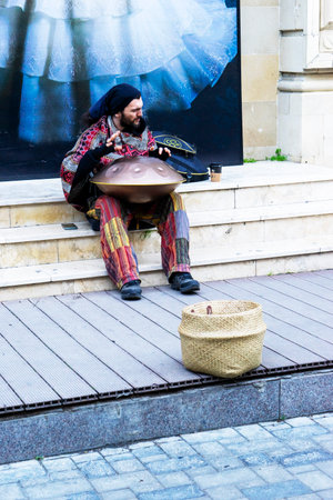 BAKU, AZERBAIJAN - DECEMBER 02, 2023 : A young guy with dreadlocks and a beard plays a percussion...