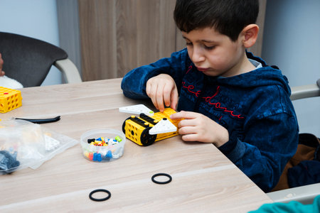 AZERBAIJAN, BAKU - JUNE 24, 2022 : A little boy sits at a table and collects a construction kit.のeditorial素材