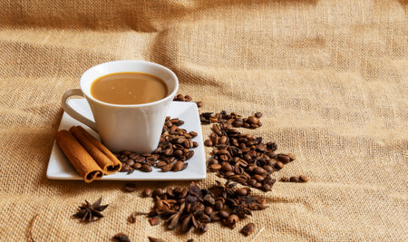 A white cup with a saucer and coffee and coffee beans on a brown cloth background.の写真素材