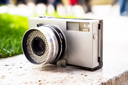 Vintage digital camera on boulder over blurred nature background. Shallow depth of field with focus on camera. Outdoor. Retro picture style.の写真素材