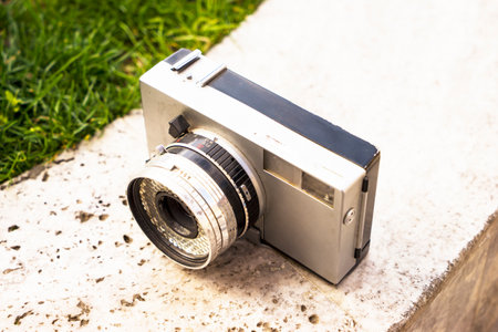 Vintage digital camera on boulder over blurred nature background. Shallow depth of field with focus on camera. Outdoor. Retro picture style.の写真素材