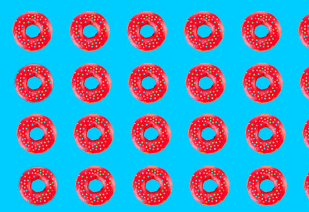 Pink glazed donut pattern on blue pastel background. Creative conceptの写真素材