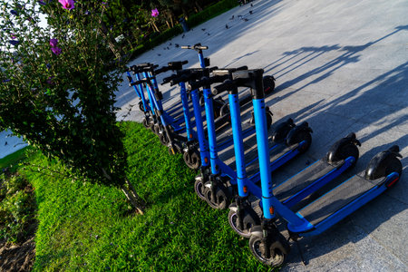 Blue electric scooters parked in the parking lot are ready for use - this is a very familiar vehicle that allows you to move around without polluting the environment. Environmentally friendly transport.の写真素材