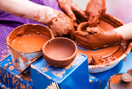 Hands of male potter, ceramist making of an earthenware pot. Potter teaches the student to make a pitcher on a pottery wheel.の写真素材