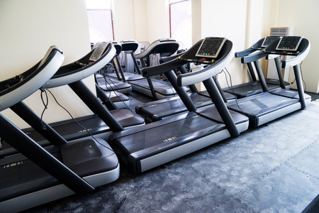 Modern gym interior with equipment. Fitness club with row of treadmills for fitness cardio training in evening backlight.の写真素材