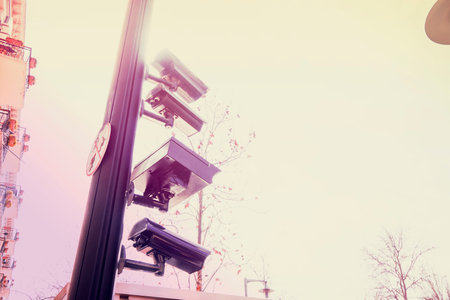 four cctv installed on metal light pole, blue sky backgroundの写真素材