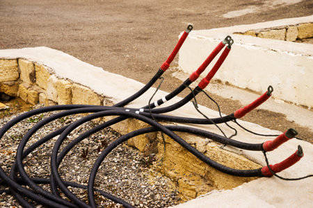 The electric cable sticks out of the ground. A bare wire presents a danger to people and animals.の写真素材
