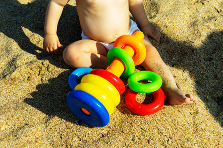 A cute boy is sitting on the beach and plays with toys. The concept of travel and adventure. Family trip.の写真素材