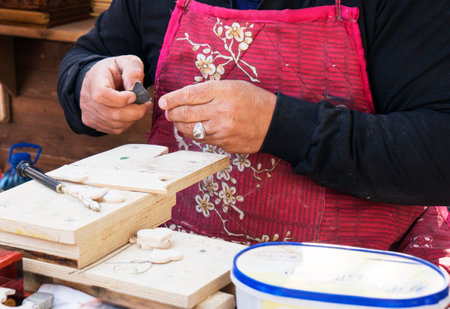 Fez, Morocco - January 07, 2020: Unknown man in his wood working or carving workshop near street market. many wooden souvenirs and products around himの写真素材
