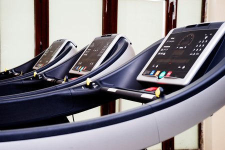 Modern gym interior with equipment. Fitness club with row of treadmills for fitness cardio training in evening backlight. Healthy lifestyle conceptの写真素材