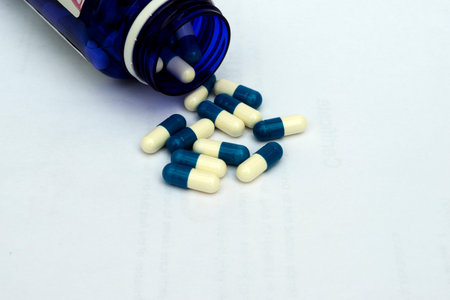 a blue bottle with white and blue pills on a white backgroundの写真素材