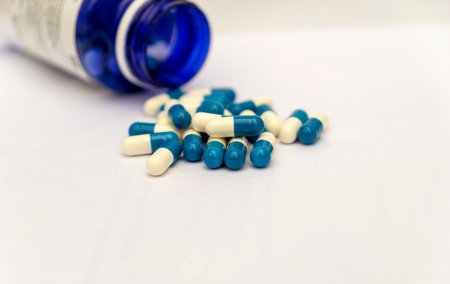 a blue bottle with white and blue pills on a white backgroundの写真素材