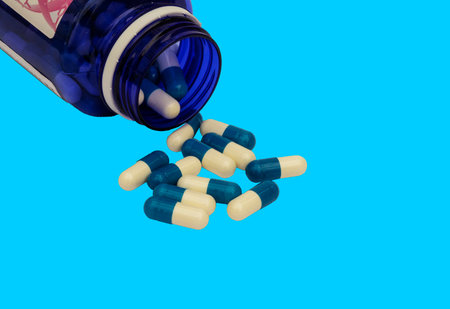 a blue bottle with white and blue pills on a blue backgroundの写真素材