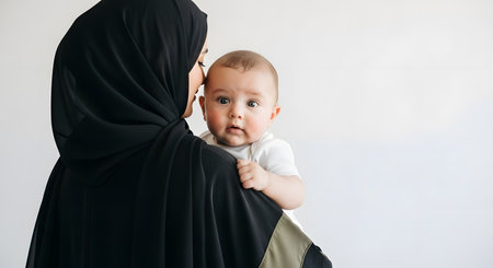 A loving Muslim mother in a hijab cradles her precious baby, sharing a tender moment of connection and maternal affection.の素材