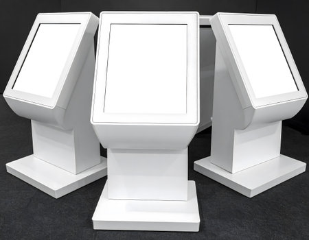 Three identical white interactive touch screen information kiosks are displayed in a group against a dark background.の素材