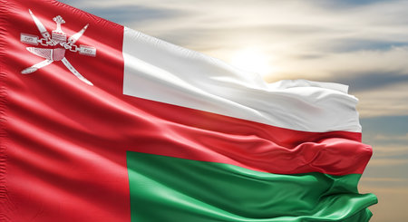 The vibrant Omani flag, featuring red, white, and green bands with the national emblem, billows dramatically in the wind.の素材