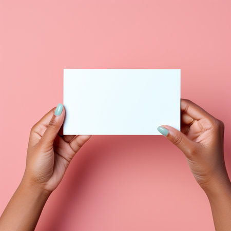 Female hands holding blank business card on pink background. Flat lay, top view.の素材