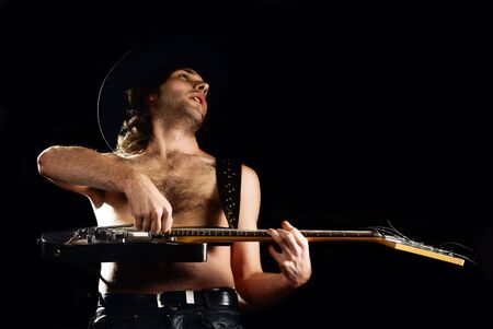 Rock'n'roll young man playing guitar. Black background. Studio shot.の写真素材