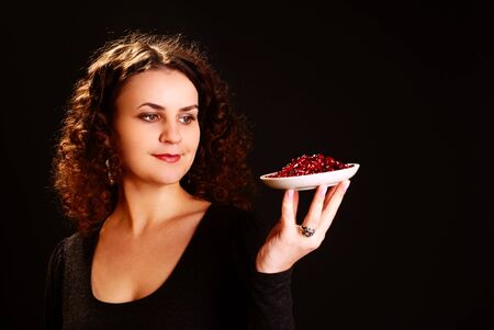 Portrait of a beautiful woman with seeds of pomegranate. Studio shot.の写真素材