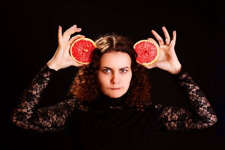 Portrait of young beautiful woman with grapefruit. Studio shot.の写真素材