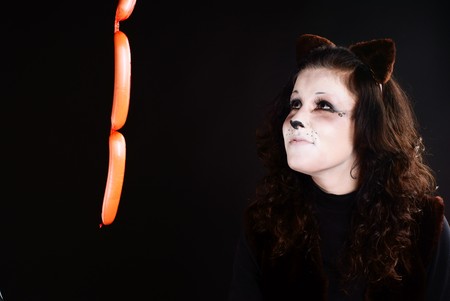 Portrait of cat girl wathcing at sausage. Studio shot.の写真素材