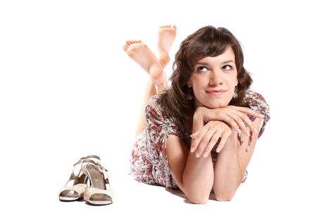 Young woman lying on the floor with shoes. White background. Studio shot.の写真素材