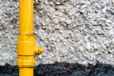 Yellow Water Pipe with Textured Rubble Stone Wall on Background, Abstract Background, Natural...