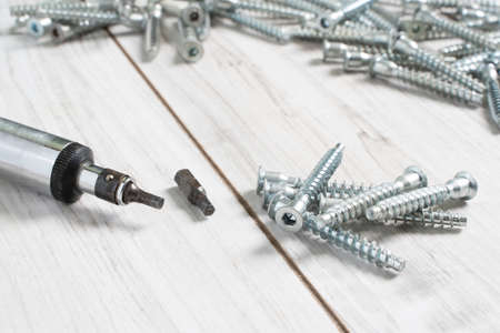 Group of Screw bolts for furniture assembling with a screwdriver on wooden background. Stock photo.の写真素材