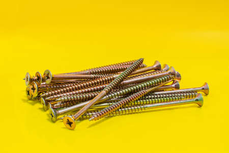 Metal Screws on yellow background. Close up stock photo.