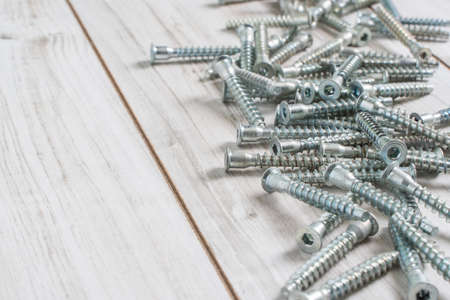 Group of Screw bolts for furniture assembling on wooden background. Stock photo with copyspace for...
