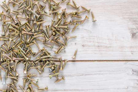 Metal Screws on wooden background. Flat lay top view with a copyspace for text. Stock photo