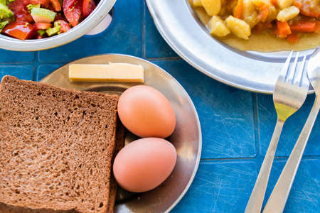 Simple Rustic Food Breakfast Set. Boiled Eggs, Bread, Butter Vegetable Salad, Stewed Potatoes with...