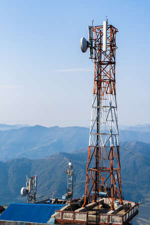 Telecommunication tower with antennas. Wireless Communication Antenna Transmitter with Mountains on Background. Stock Photo.のeditorial素材