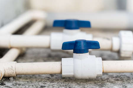White plastic water pipes with blue faucet, parts of a home water supply system, close up stock photoの写真素材