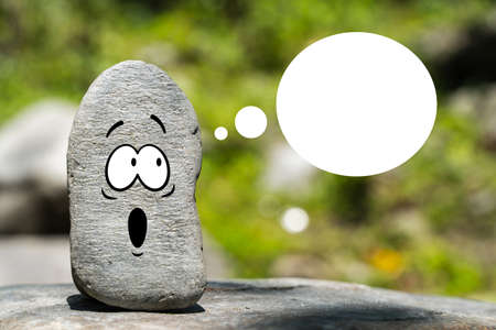 Natural stone with drawn funny face and speech bubble with copy space. Empty template for advertisement, sale banner, motivation poster etc.の写真素材