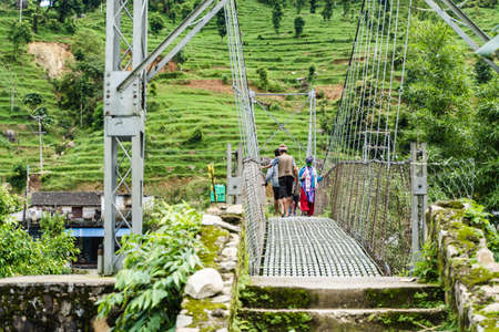 Nepal, Ghatchhina village, July of 2020: Local people crossing the river on a suspension bridgeのeditorial素材