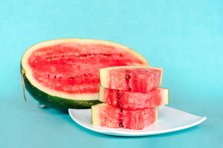 Water melon slices on a plate on blue background. Juicy fresh tasty summer dessert. Stock photo