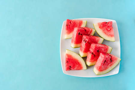 Water melon slices on a plate on blue background. Juicy fresh tasty summer dessert. Top view with...