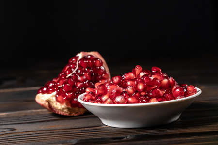 Garnet seeds and cracked pomegranate on wooden backgroundの写真素材