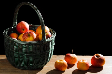 Apples in basket on old plank on black backgroundの写真素材