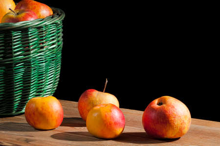Apples in basket on old plank on black backgroundの写真素材