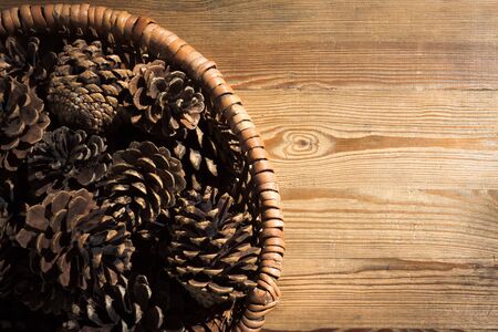 Pine Cone in wicker basket on old wood backgroundの写真素材