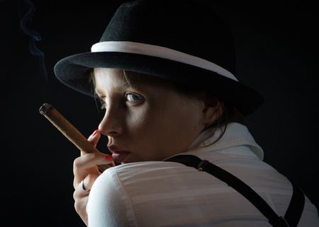 Woman in black hat with cigar in black isolatedの写真素材