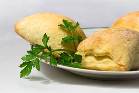 Homemade small pie with parsley on white plate