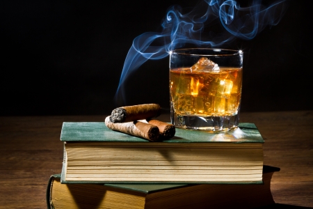 Cigar with blue smoke and whisky on ice and two books volumeの写真素材