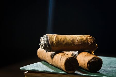Tree cigars laying on leather bookの写真素材