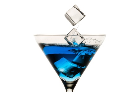Dropping ice cubes into martini glasses on white backgroundの写真素材