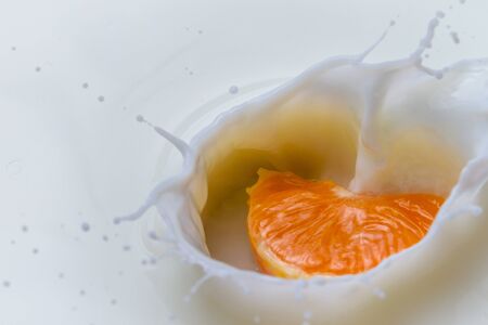 Falling mandarin into milk makes a splashの写真素材